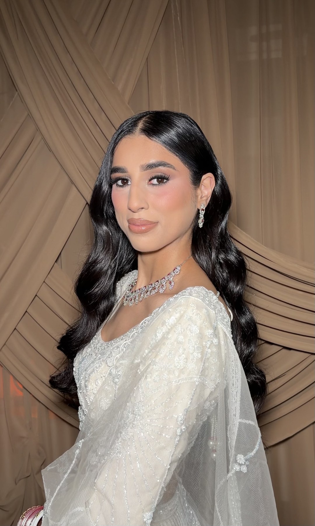 Bridal look — white embellished saree, brown draped backdrop