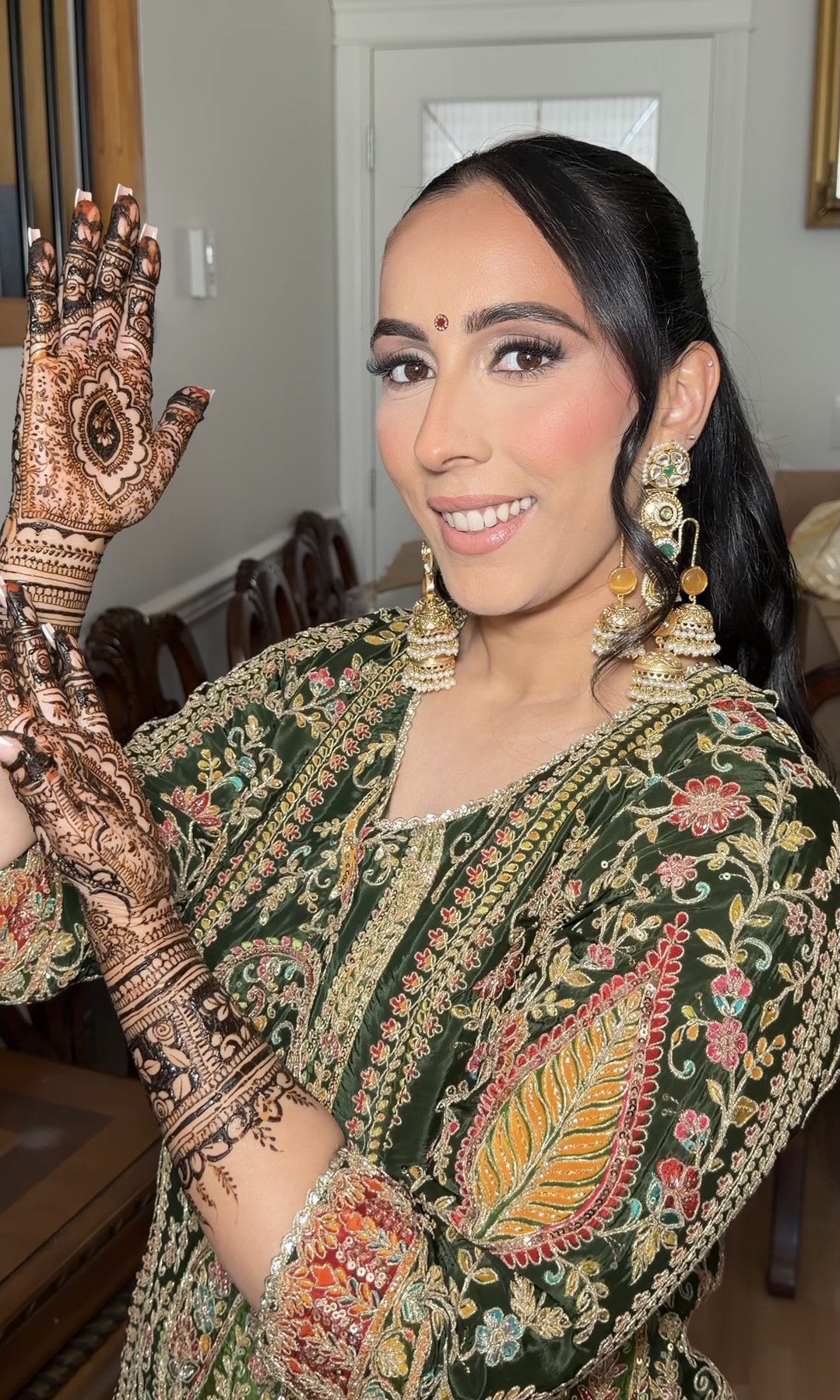Bridal look — olive green outfit with mehndi, smiling